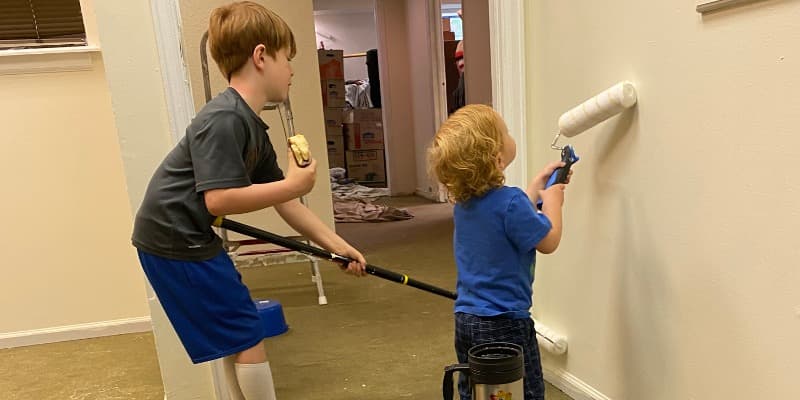 Two children painting a wall with rollers inside the Hub's new building